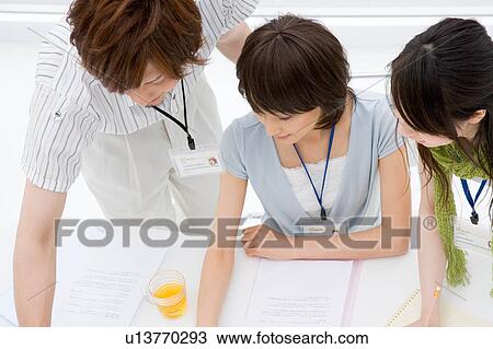 Stock Image - Three people looking at computer. Fotosearch