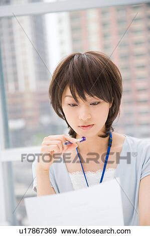 Stock Photo - Young woman looking at document. Fotosearch