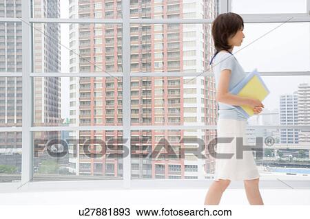 Young woman walking in office View Large Photo Image Stock Image - Young woman walking in office. Fotosearch