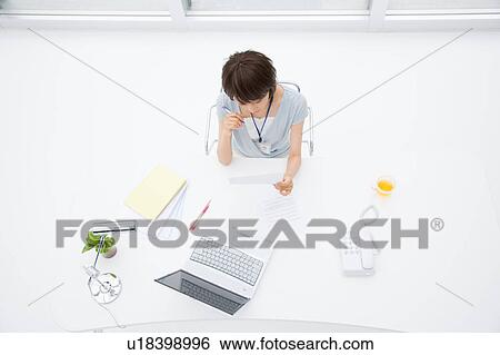 Stock Photograph - Young woman working at her desk. Fotosearch
