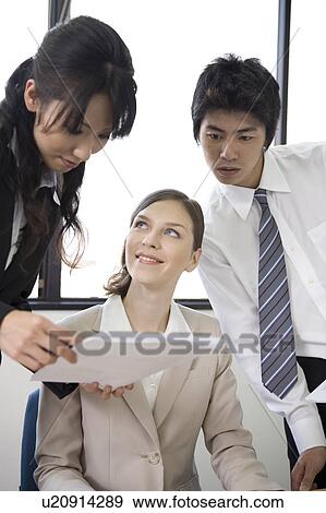 Stock Photo - Three business people looking at documents. Fotosearch