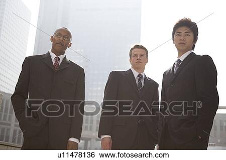Three businessmen standing looking at camera View Large Photo Image Stock Photograph - Three businessmen standing looking at camera. Fotosearch