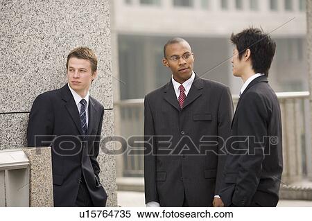 Three businessmen talking in front of building View Large Photo Image Stock Photography - Three businessmen talking in front of building. Fotosearch