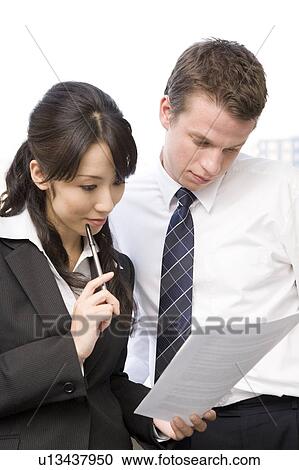 Stock Image - Two business people looking at document. Fotosearch
