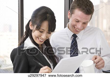 Stock Photo - Two business people looking at document. Fotosearch