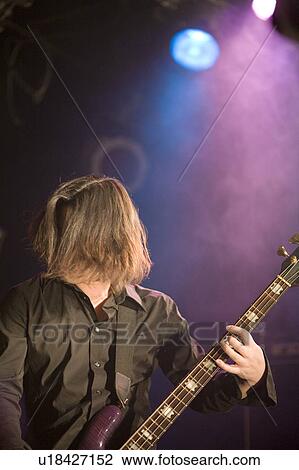 Stock Image - Young man playing bass guitar on stage. Fotosearch