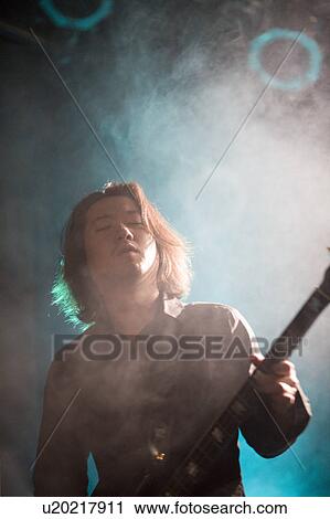 Stock Image - Young man playing bass guitar on stage. Fotosearch