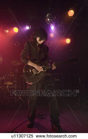 Stock Photography - Young man playing electric guitar on stage. Fotosearch