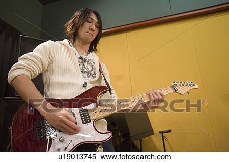Young man playing electric guitar View Large Photo Image Stock Photography - Young man playing electric guitar. Fotosearch
