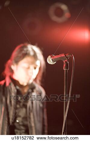 Stock Image - Young man standing in front of microphone. Fotosearch
