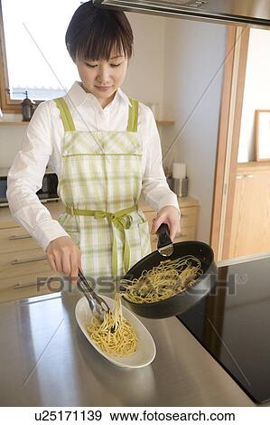 Stock Photo - Young woman cooking spaghetti. Fotosearch