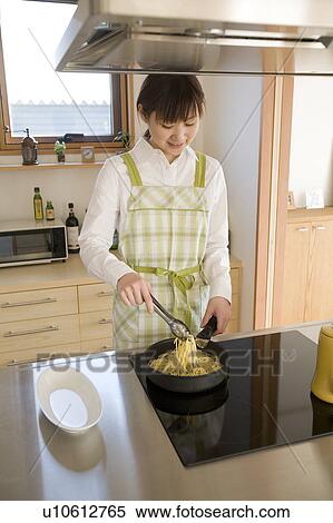 Stock Photography - Young woman cooking spaghetti. Fotosearch
