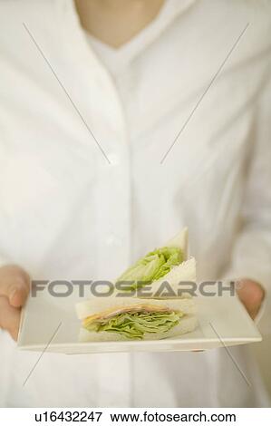 Stock Photo - Young woman holding plate of sandwich. Fotosearch