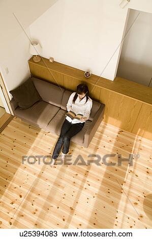Young woman reading book sitting on sofa View Large Photo Image Stock Image - Young woman reading book sitting on sofa. Fotosearch