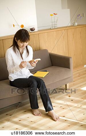 Young woman reading book sitting on sofa View Large Photo Image Stock Photograph - Young woman reading book sitting on sofa. Fotosearch