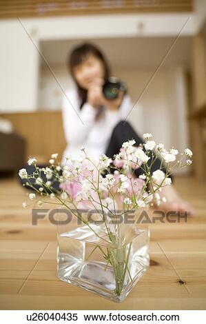 Stock Photography - Young woman taking photo of flowers. Fotosearch