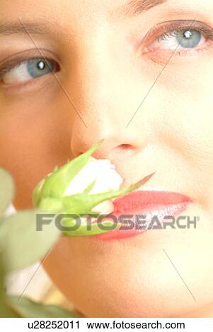 Stock Image - Close-up of female face with single white rose. Fotosearch