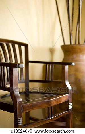 Stock Image - Antique wood chair next to terra cotta pot. Fotosearch