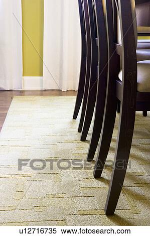 Stock Photography - Chair legs on rug in dining room. Fotosearch