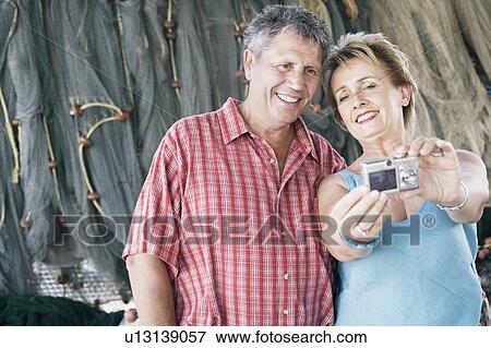 Close-up of a mature woman with a senior man taking a photograph of themselves View Large Photo Image Stock Photo - Close-up of a mature woman with a senior man taking a photograph of themselves. Fotosearch