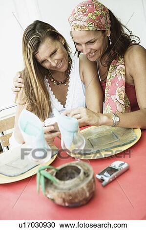 Close-up of two mid adult women looking at a digital camera and smiling View Large Photo Image Stock Image - Close-up of two mid adult women looking at a digital camera and smiling. Fotosearch
