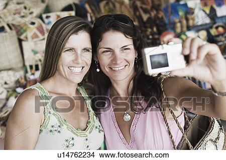 Close-up of two mid adult women taking a photograph of themselves View Large Photo Image Picture - Close-up of two mid adult women taking a photograph of themselves. Fotosearch