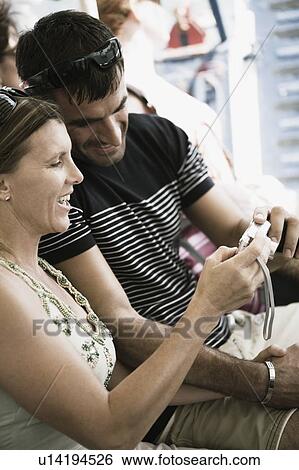Mid adult couple looking at a digital camera and smiling View Large Photo Image Stock Photograph - Mid adult couple looking at a digital camera and smiling. Fotosearch