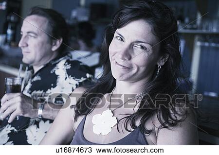 Mid adult woman smiling with a mid adult man holding a glass of drink beside her View Large Photo Image Stock Image - Mid adult woman smiling with a mid adult man holding a glass of drink beside her. Fotosearch
