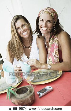 Picture - Portrait of two mid adult women holding a digital camera and smiling. Fotosearch