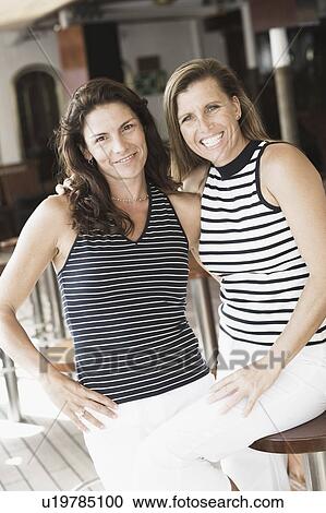 Portrait of two mid adult women with their arms around each other and smiling View Large Photo Image Stock Image - Portrait of two mid adult women with their arms around each other and smiling. Fotosearch