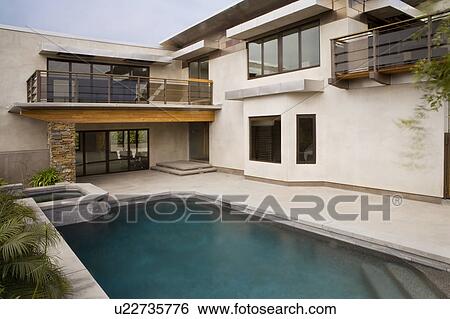 Stock Photograph - Rear exterior of modern home and swimming pool. Fotosearch