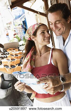 Stock Photo - Close-up of a mid adult couple holding a catalog and smiling. Fotosearch