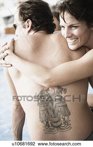 Stock Image - Close-up of a mid adult woman snuggling on a mid adult man and smiling. Fotosearch