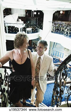 Picture - Mature woman and a senior man moving up on a staircase of a ship. Fotosearch