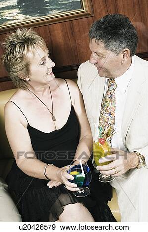 Mature woman with a senior man holding glasses of cocktail and looking at each other View Large Photo Image Stock Photo - Mature woman with a senior man holding glasses of cocktail and looking at each other. Fotosearch