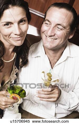 Mid adult couple holding glasses of cocktail and smiling View Large Photo Image Stock Photography - Mid adult couple holding glasses of cocktail and smiling. Fotosearch