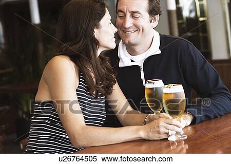 Mid adult couple looking at each other and holding beer in stem glasses View Large Photo Image Stock Photography - Mid adult couple looking at each other and holding beer in stem glasses. Fotosearch