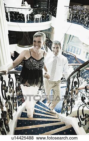 Mid adult couple moving up on a staircase of a cruise ship and smiling View Large Photo Image Stock Photo - Mid adult couple moving up on a staircase of a cruise ship and smiling. Fotosearch