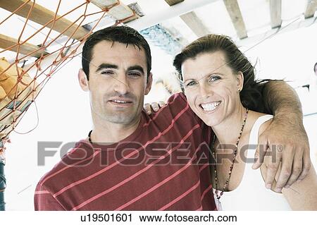 Stock Image - Mid adult man with his arm around a mid adult woman and smiling. Fotosearch
