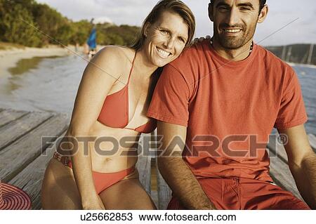Portrait of a mid adult couple sitting on a pier and smiling View Large Photo Image Stock Image - Portrait of a mid adult couple sitting on a pier and smiling. Fotosearch