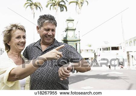 Stock Photography - Senior man checking the time with a mature woman standing beside him. Fotosearch