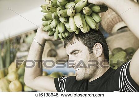 Close-up of a mid adult man carrying a bunch of bananas on his head View Large Photo Image Stock Photograph - Close-up of a mid adult man carrying a bunch of bananas on his head. Fotosearch