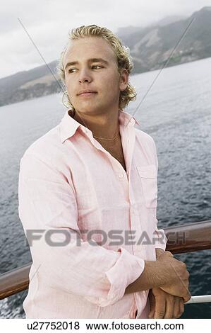 Close-up of a young man standing on a boat deck View Large Photo Image Stock Photo - Close-up of a young man standing on a boat deck. Fotosearch