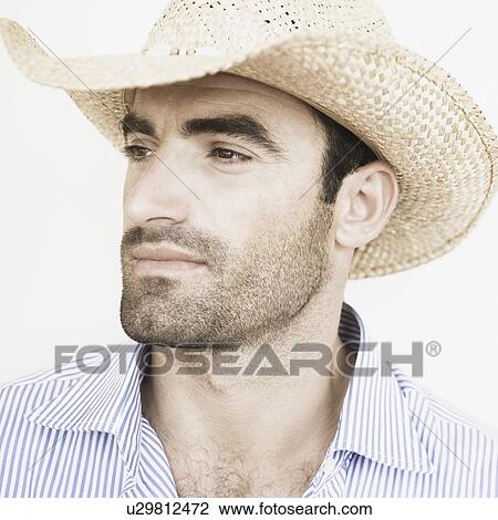 Stock Image - Close-up of a young man wearing a straw hat. Fotosearch