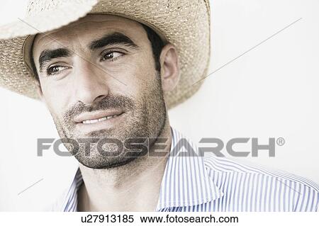 Stock Photography - Close-up of a young man wearing a straw hat. Fotosearch