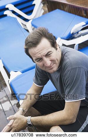 High angle view of a mid adult man sitting on a lounge chair View Large Photo Image Stock Photo - High angle view of a mid adult man sitting on a lounge chair. Fotosearch