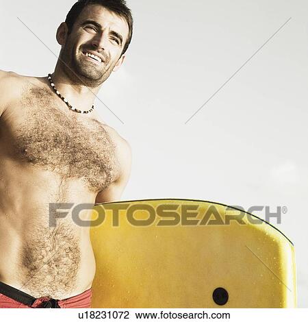 Low angle view of a mid adult man holding a surfboard View Large Photo Image Stock Image - Low angle view of a mid adult man holding a surfboard. Fotosearch