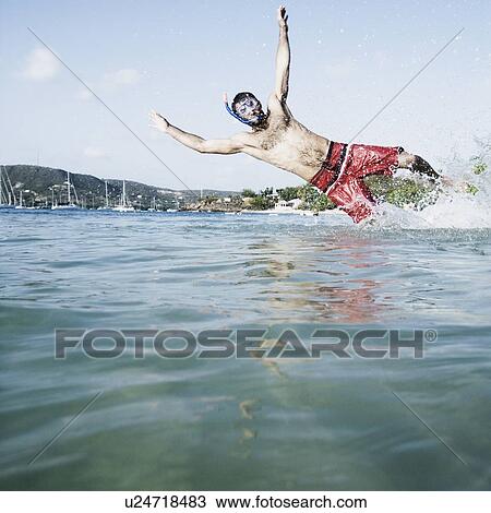 Mid adult man diving in water View Large Photo Image Stock Image - Mid adult man diving in water. Fotosearch