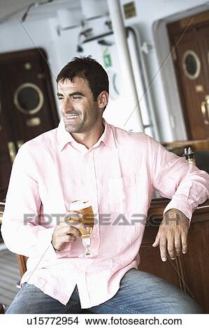 Mid adult man holding a glass of beer and smiling View Large Photo Image Picture - Mid adult man holding a glass of beer and smiling. Fotosearch