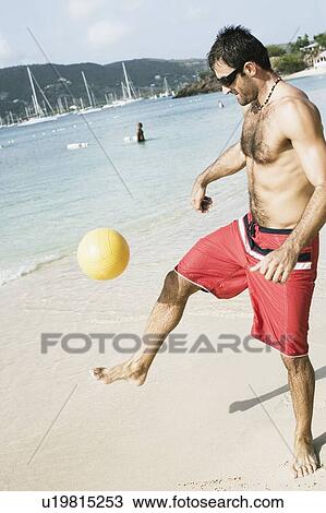 Mid adult man playing beach volleyball on the beach View Large Photo Image Stock Image - Mid adult man playing beach volleyball on the beach. Fotosearch